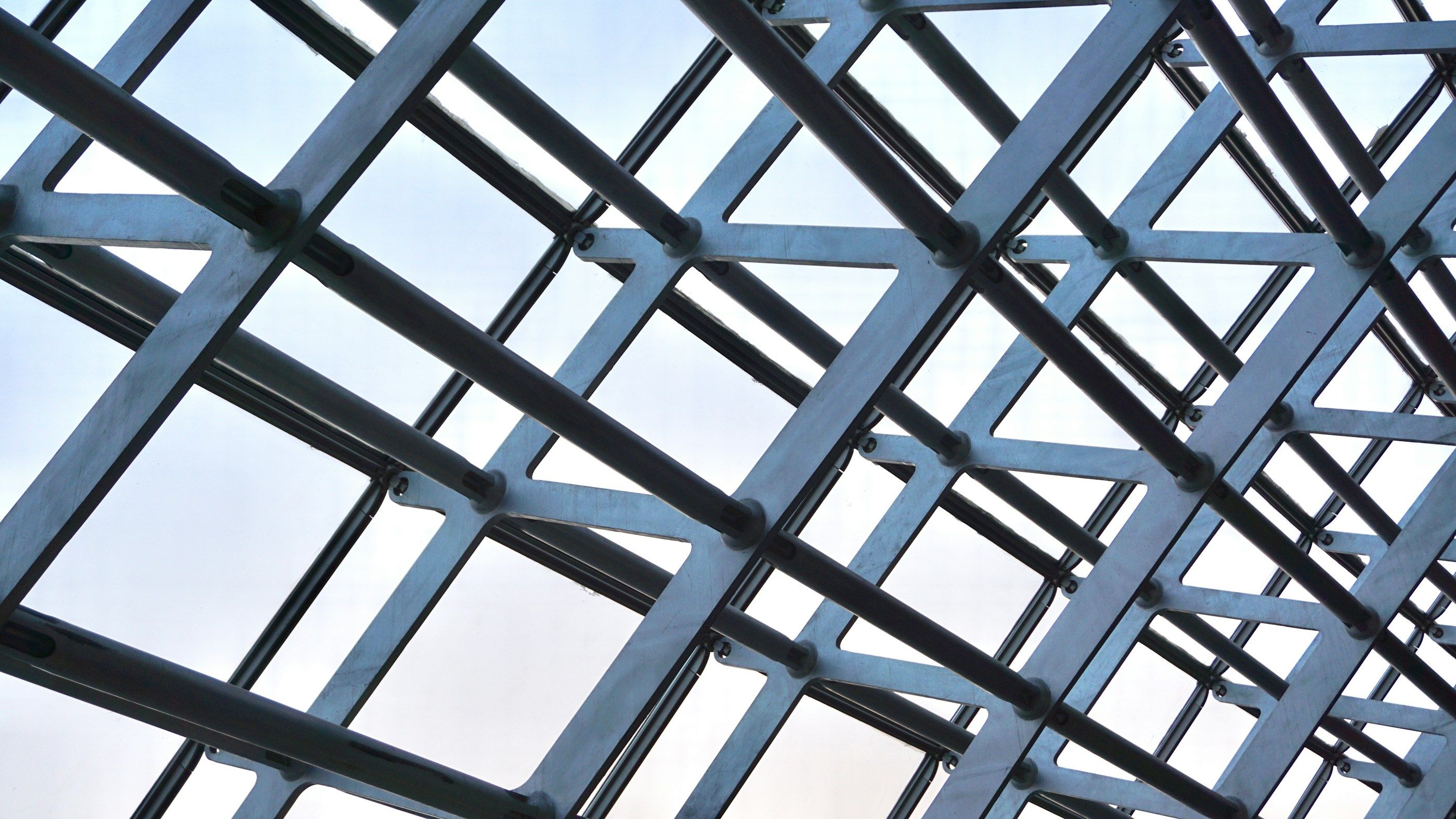 Verzinktes Stahlraster eines Glasdachs vor hellem Himmel