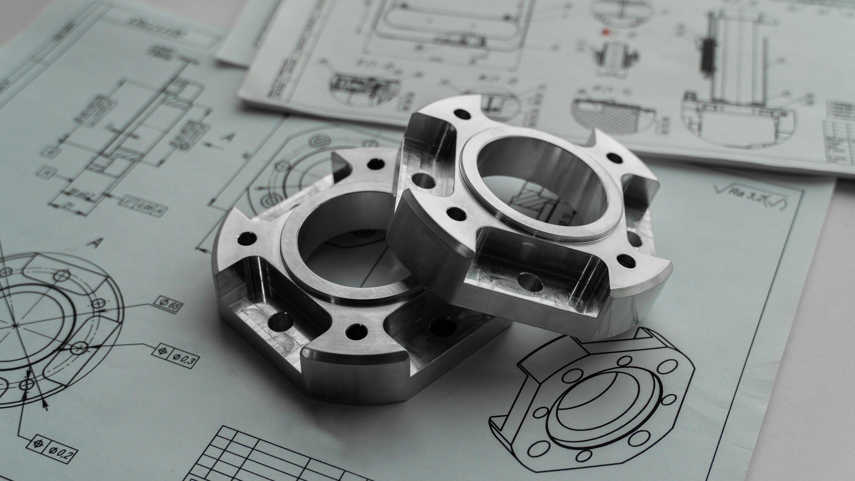Zwei gefräste Aluminiumflansche auf technischen Zeichnungen mit Bemaßung und Toleranzangaben